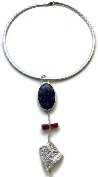 Pendant with three components: a beautiful navy blue lapis lazuli oval flecked with gold veining, a rough dark pink tourmaline and a free form reticulated silver slice.   Hung from a 16" sterling silver smooth Omega chain.   Pendant can be worn in either direction.