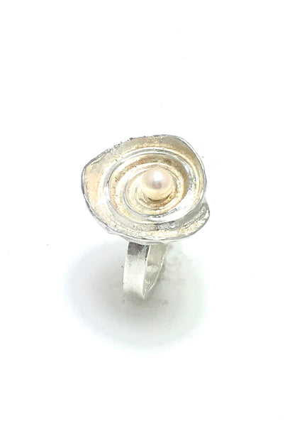 A ring made from a sea shell with the spiral cavities of the shell shining in sterling silver and a white pearl in the middle.