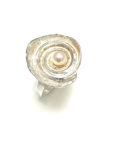 A close up showing the ring.  Sterling silver with white akoya pearl.   The internal cavities of a shell are smooth to the feel but tactile.