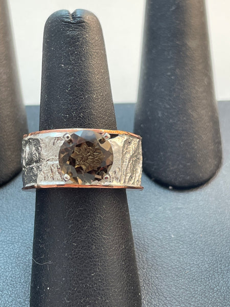 Close up photo of  a very thick band of textured reticulated silver accented with a brown smoky quartz stone. The ring also has copper and silver. It is a hollow ring. Size 8.  