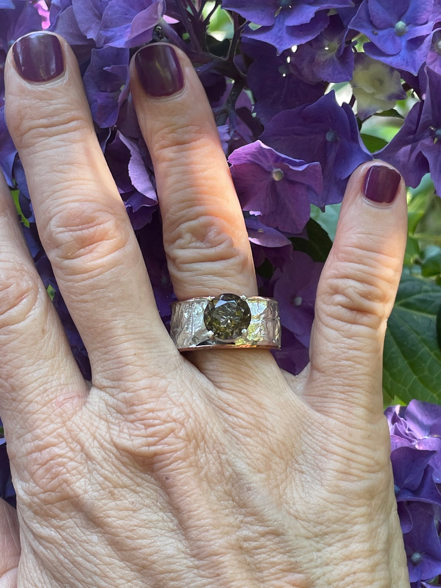A very thick band of textured reticulated silver accented with a brown smoky quartz stone.  The ring also has copper and silver.  It is a hollow ring.  Size 8