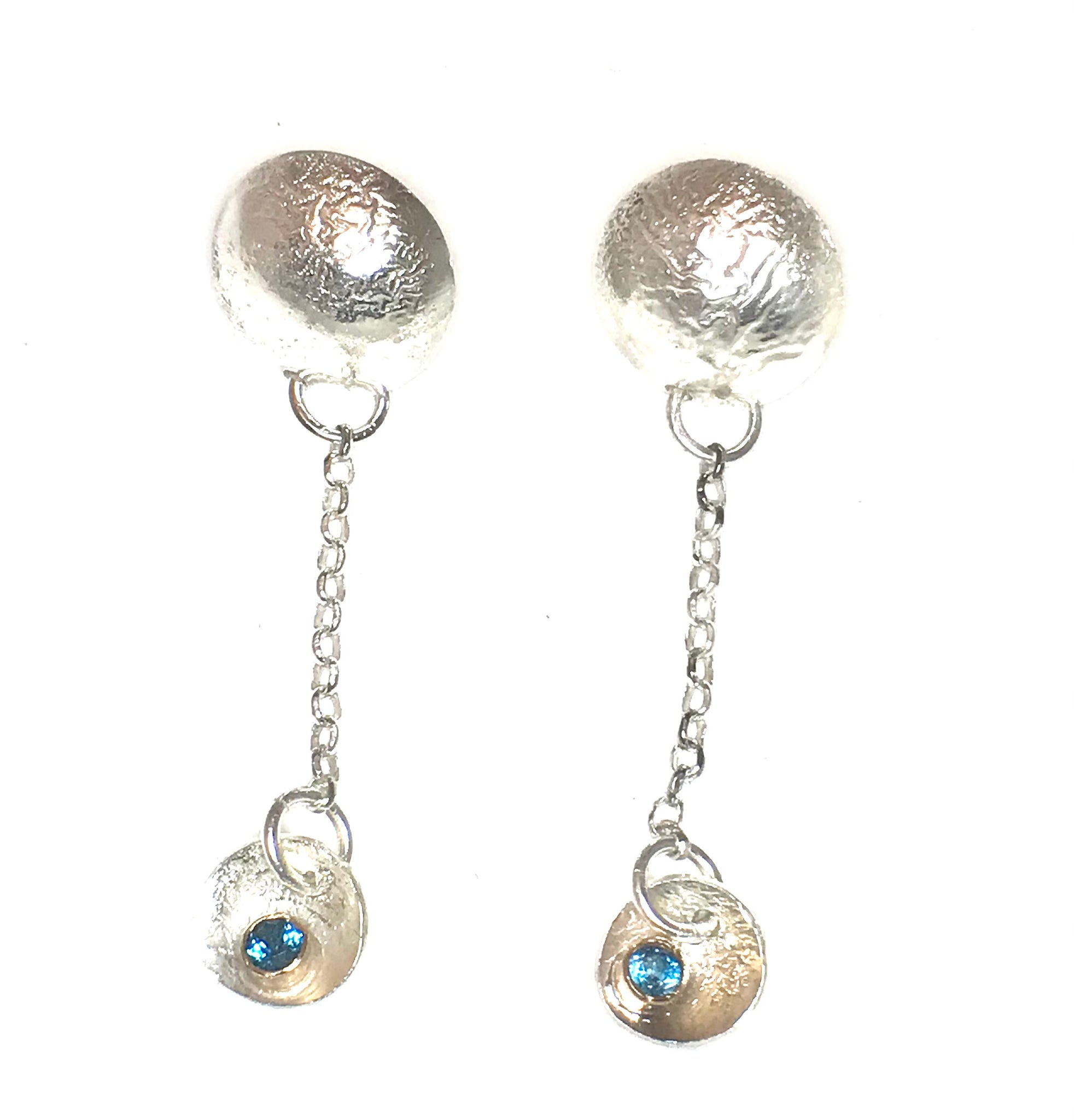 Earrings made from highly textured reticulated silver.  These earrings have posts attached to half domed moon shaped disks.   From the disks hang chain and then smaller disks in which are nestled a London blue topaz set in a gold tube set.