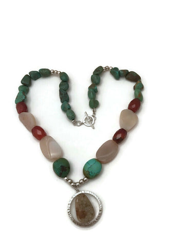 A beautiful pendant made up of green turquoise from New Mexico, agate druzies which are sparkling and very textured with soft red carnelian accents.   The focal point is another agate druzy with caramel and brown tones.   Druzies are sparkling crystals embedded on agate bases.   Natural growing in nature.